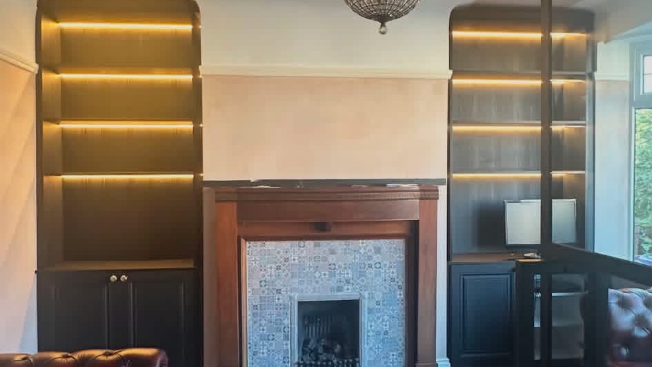 Bespoke alcove shelving with integrated lighting either side of a fireplace