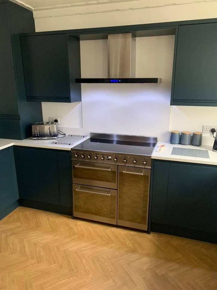 Dark teal handleless kitchen with a range cooker and herringbone floor