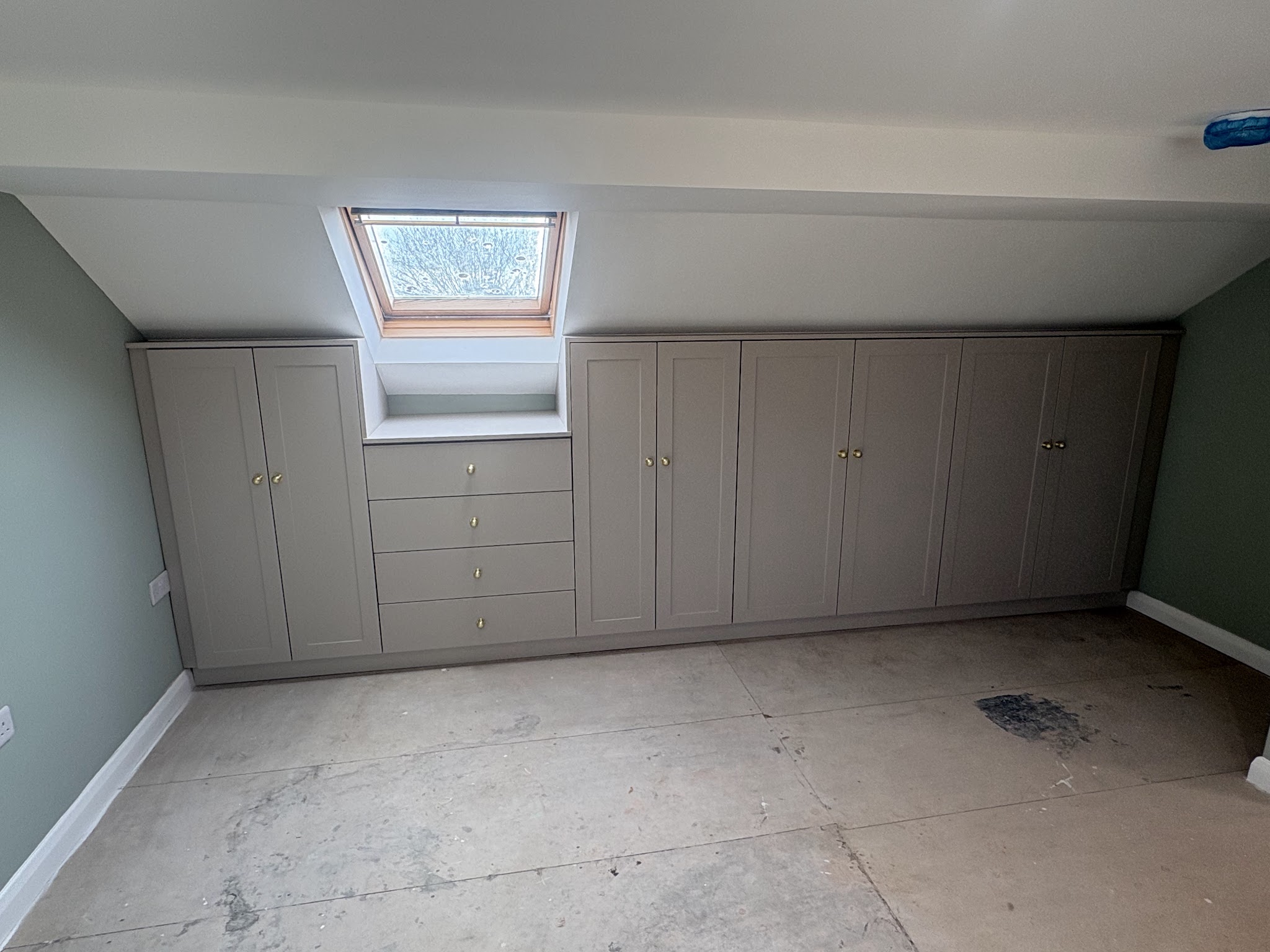 Fitted wardrobes built around a loft skylight with a window seat