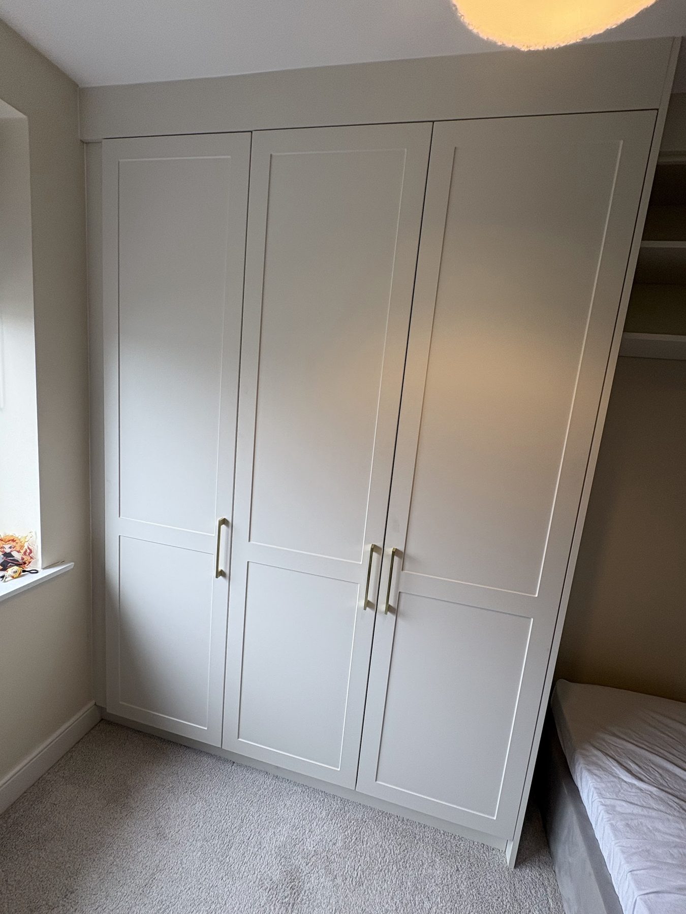 Floor to ceiling cream shaker fitted wardrobes with brass handles