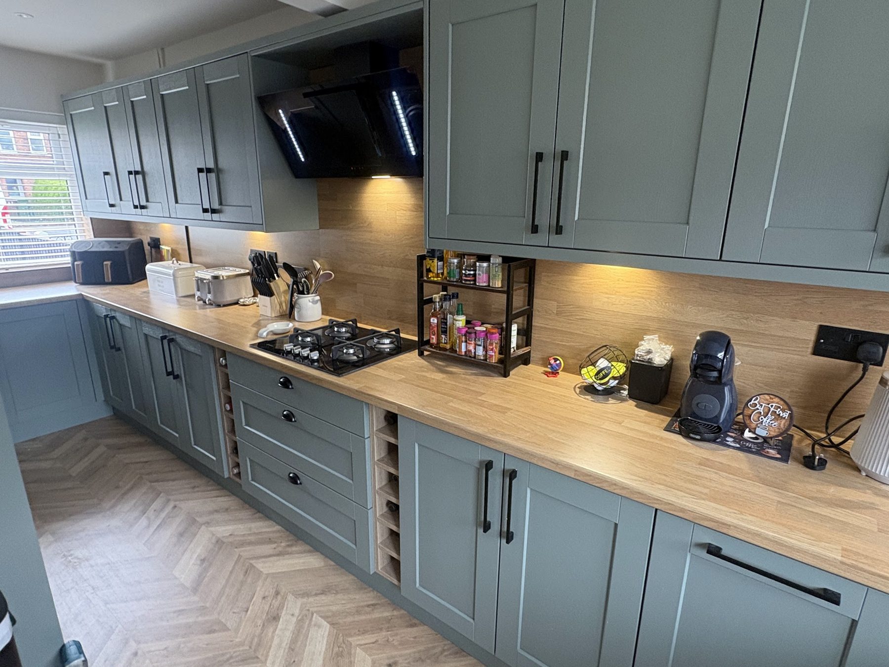 A finished sage green shaker kitchen with oak worktops fitted by NRG Kitchens in Liverpool