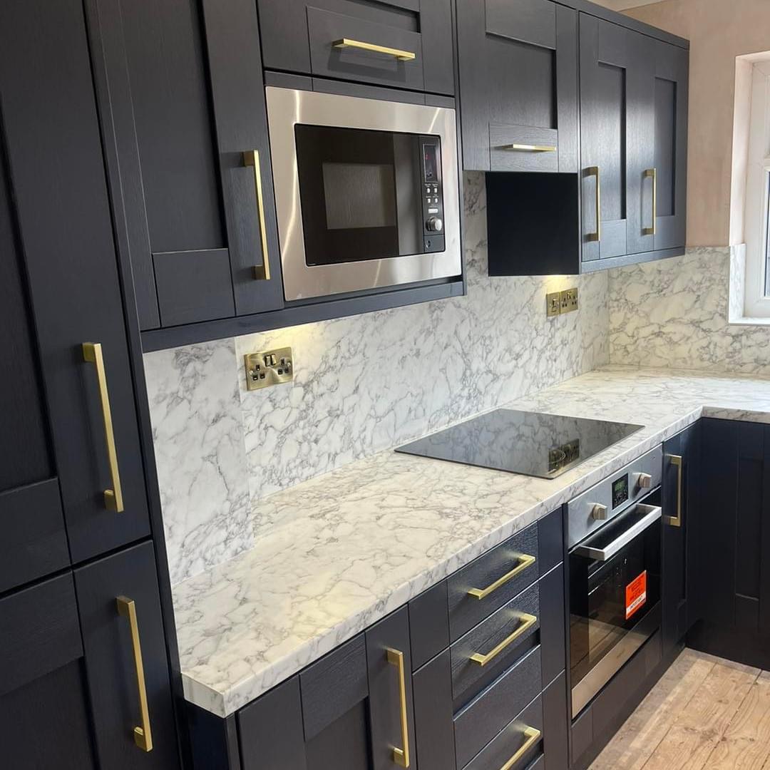 Navy shaker kitchen with brass handles and a marble effect worktop